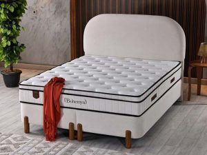 Bohemya boxspring in crèmekleurig fluweel met rond boogvormig hoofdbord en houten poten