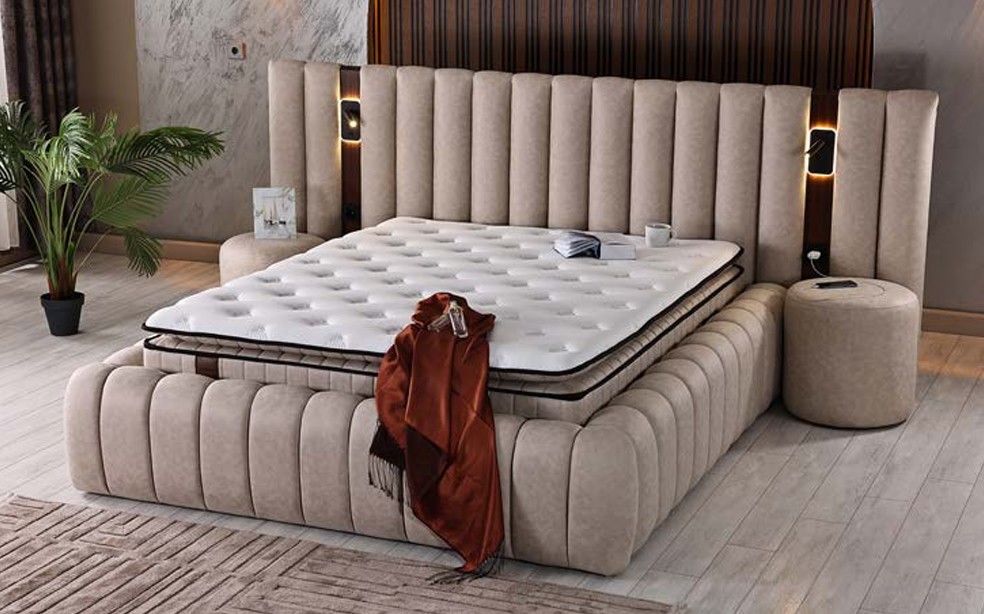 Noble boxspring in taupe suèdelook met breed geribbeld hoofdbord en geïntegreerde leeslampen